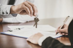 A man hands keys over to client signing a lease