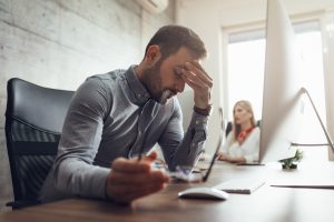 Man struggles with occupational stress while working at computer