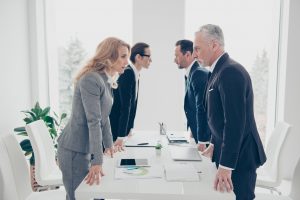 Businessmen standing at a table and looking at each other's eyes intently