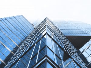 A steep ground level view of a tall building with large glass windows