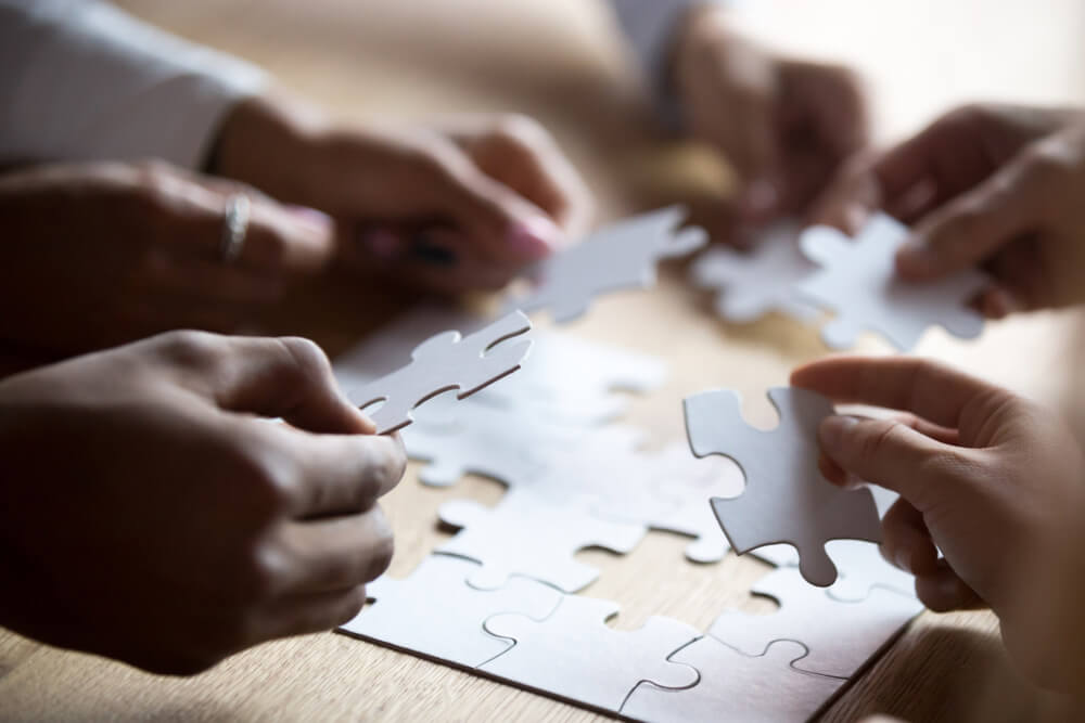 Several people putting puzzle pieces together at a table