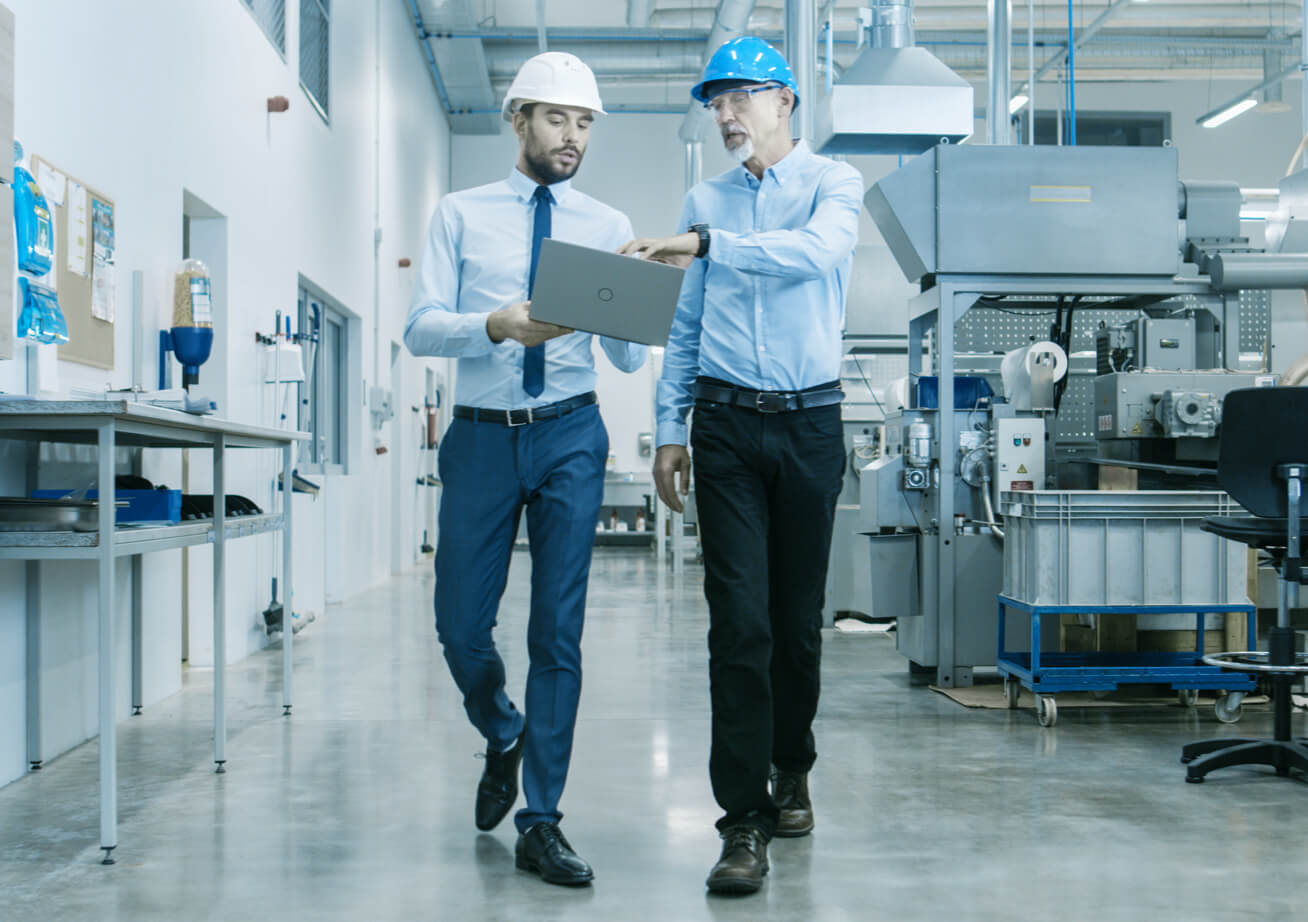 Two office employees with hard hats discussing notes in a flex space