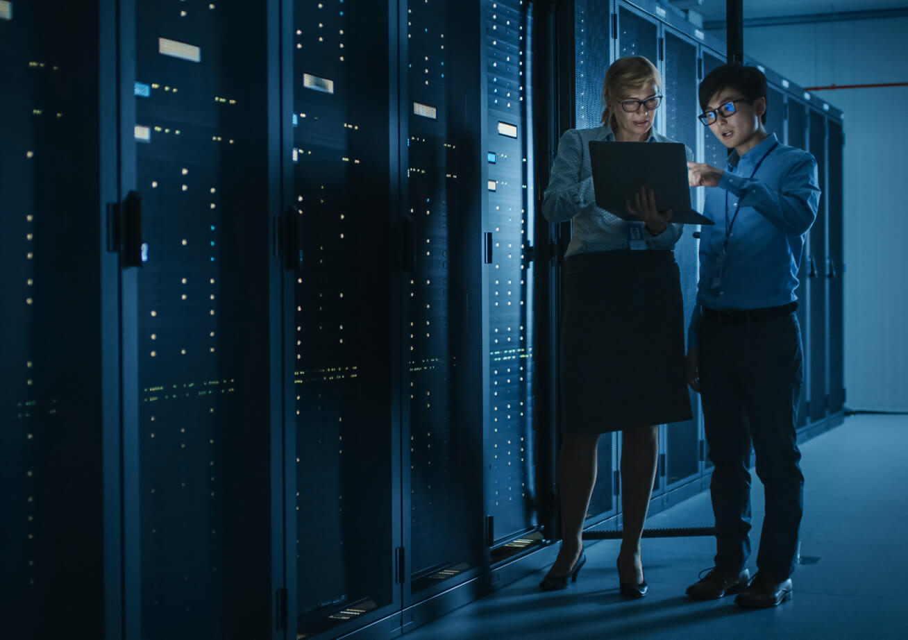 Two employees discussing work in the dark interior of a server room