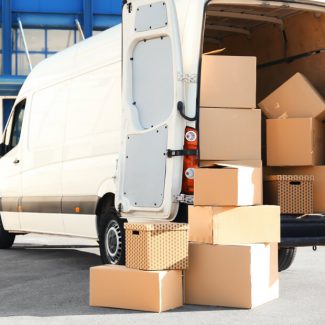 A large number of cardboard boxes stacked inside and outside of a moving van