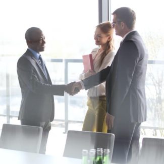 A realtor and client shake hands in a meeting room after a discussion