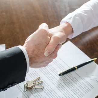 Two people shake hands after signing a lease