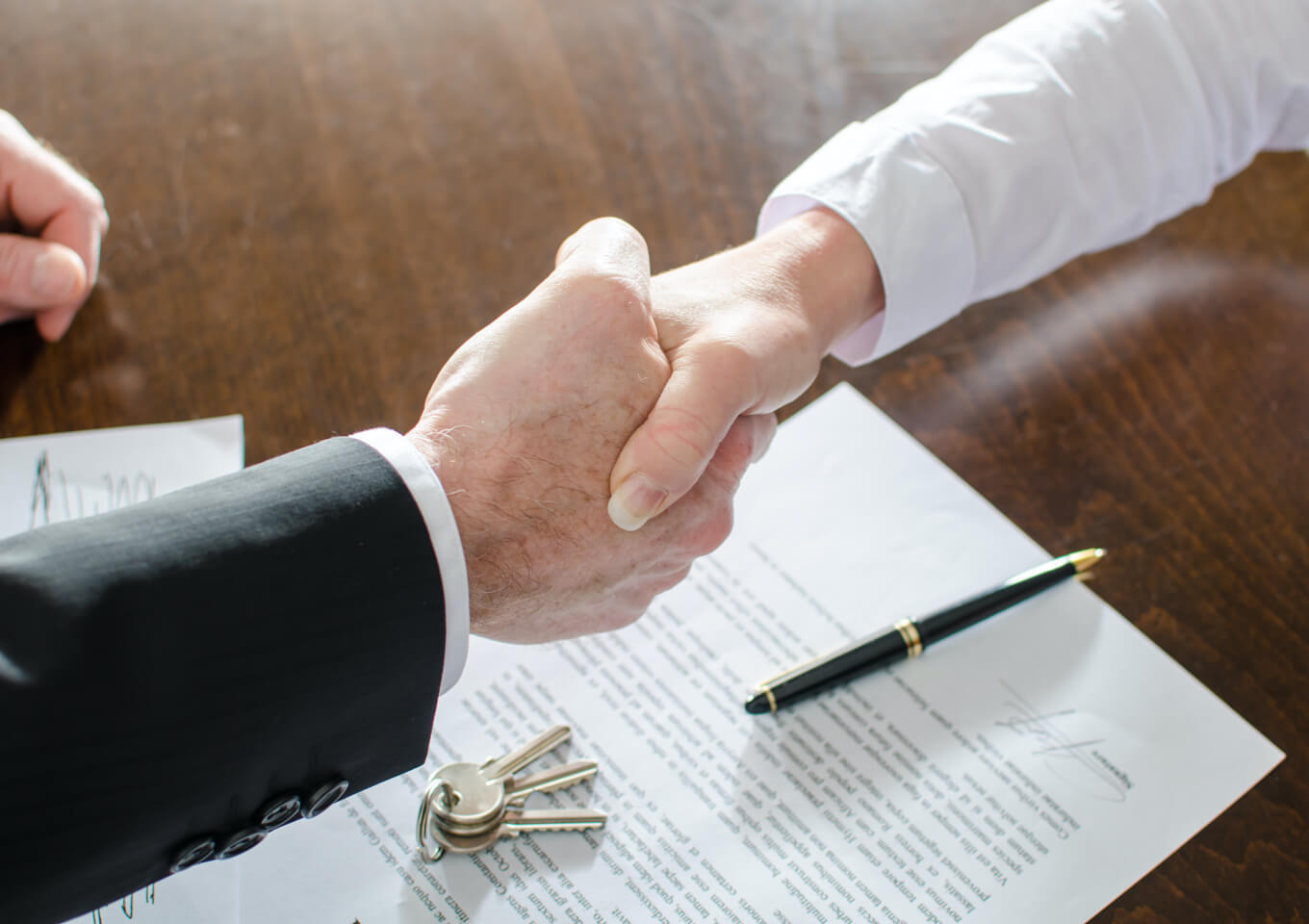 Two people shake hands after signing a lease