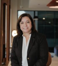 Professional woman in business attire smiling indoors.