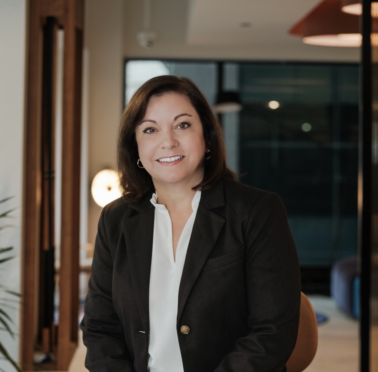 Professional woman in business attire smiling indoors.