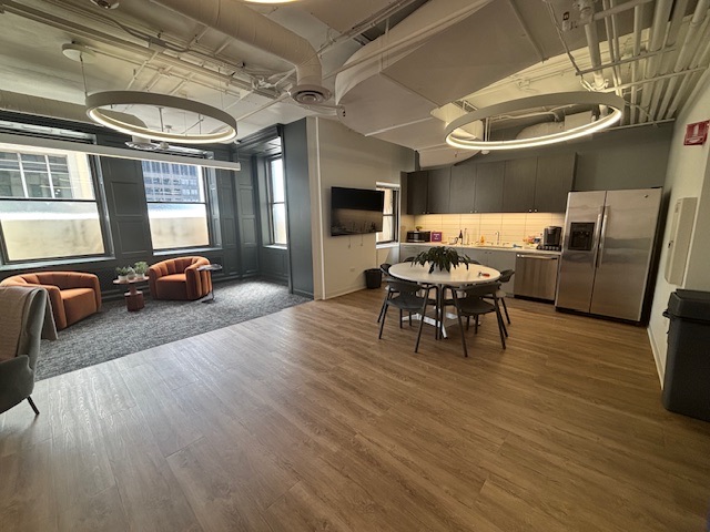 Kitchen and breakroom with an island table, full-height cabinetry and a lounge beyond