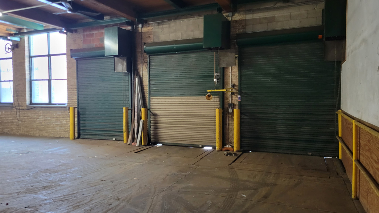 Three interior loading dock doors with rolling steel shutters and protective bollards