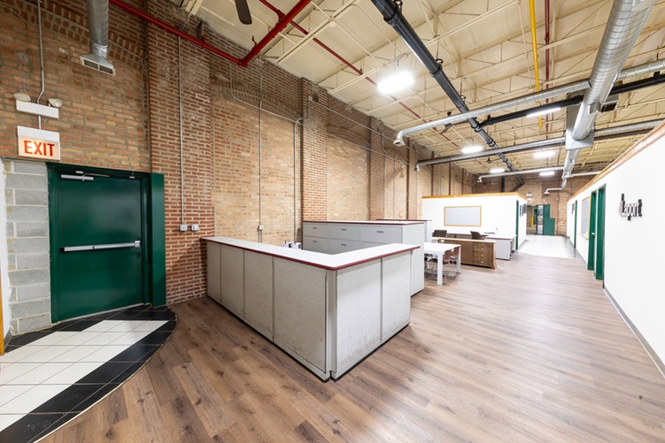 Office area inside the warehouse with wood-look flooring, exposed brick and a built-in counter
