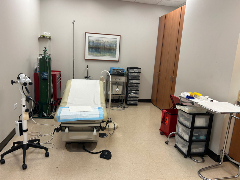 Procedure room with an exam table, equipment cart and supply storage