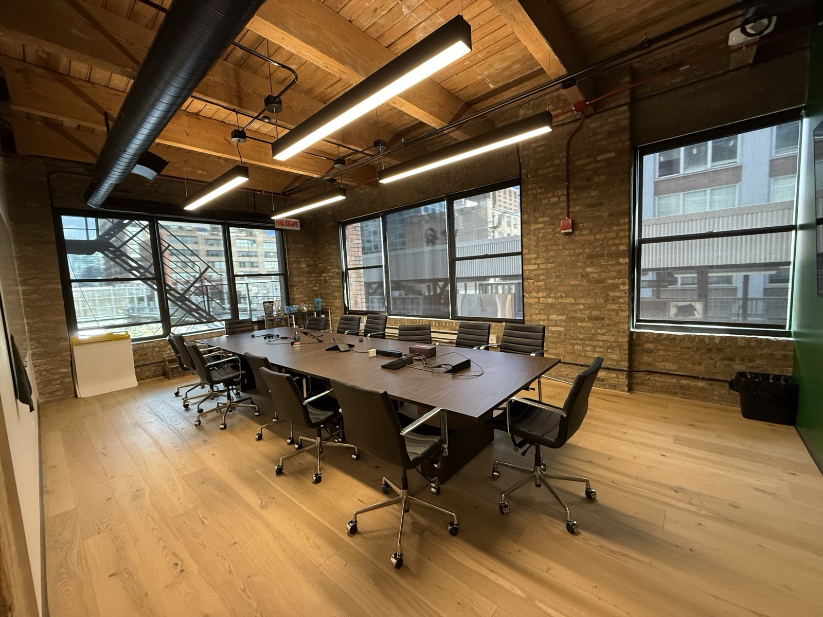 Conference room seating twelve, with exposed brick walls and windows onto the fire escape