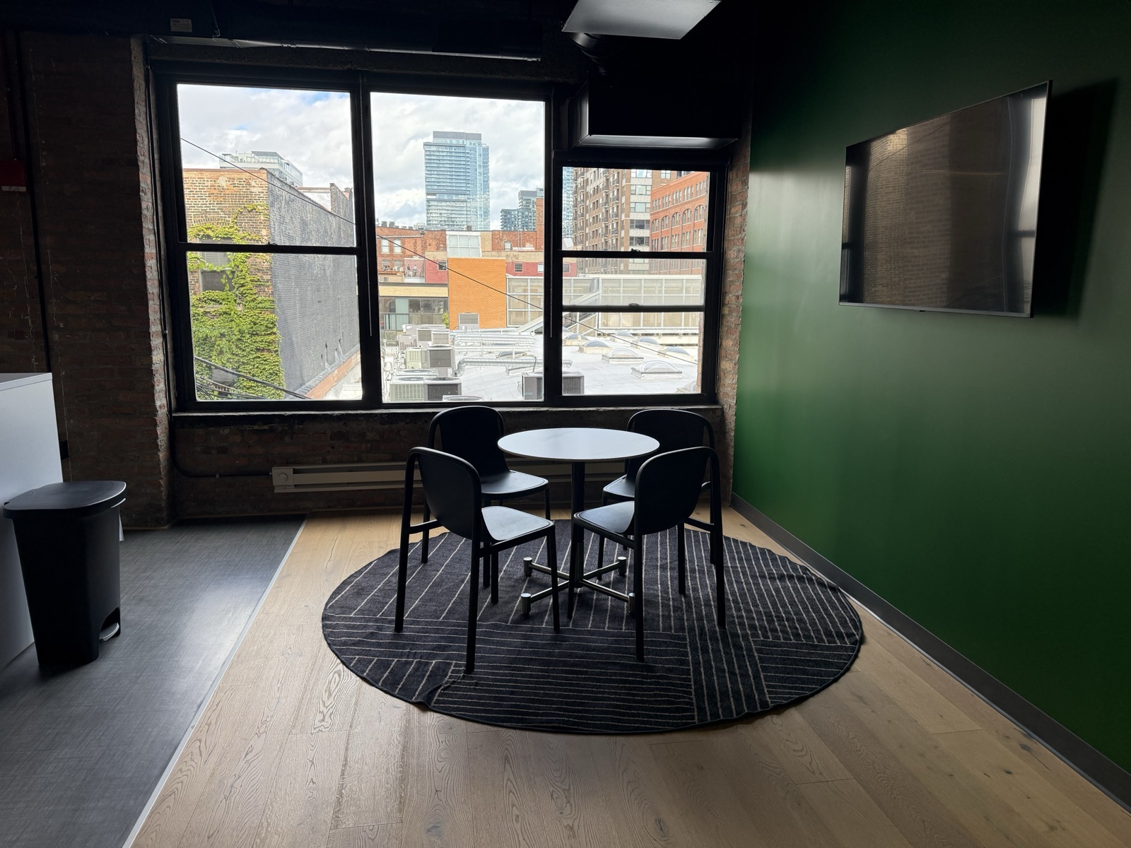 Second small meeting room with a round table, screen and windows over River North