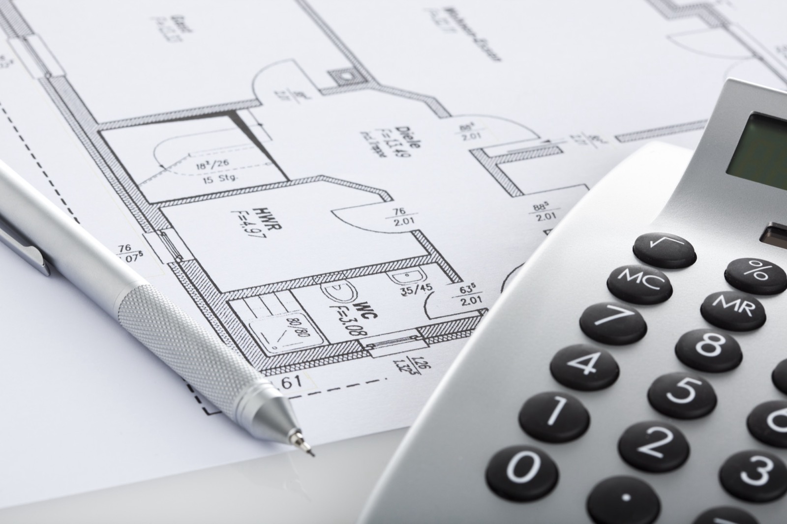 A floor plan drawing beside a calculator and pencil