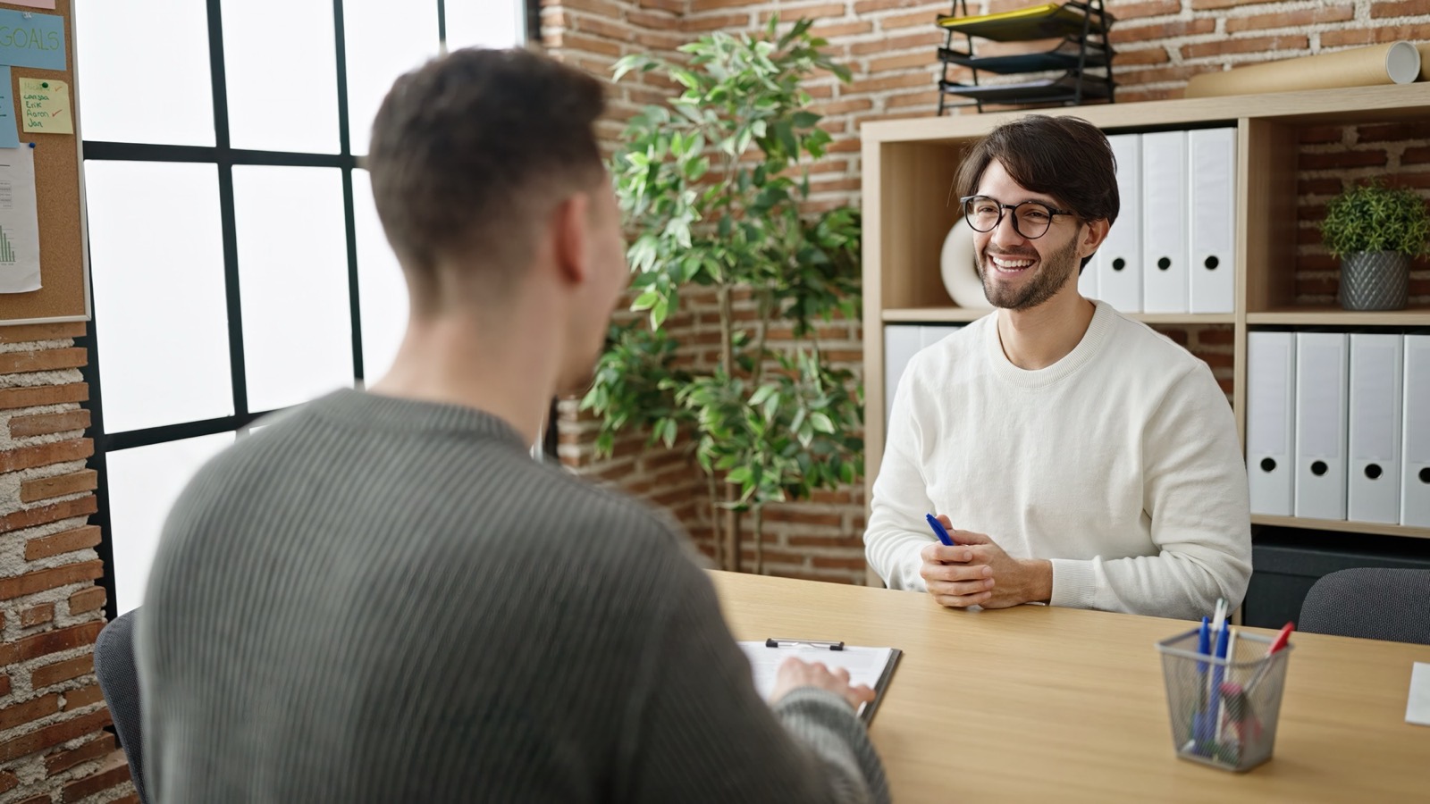 Two people talking across a desk in an office